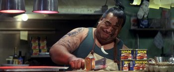 Movie still from “50 First Dates” (2004), directed by Peter Segal – A man with a tattoo on his face cutting a cake with a knife; Close Up shot, Low angle