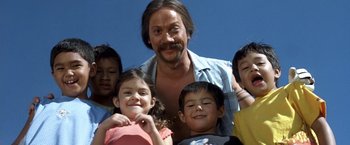 Movie still from “50 First Dates” (2004), directed by Peter Segal – A group of children and a man standing next to each other in front of a blue sky; Close Up shot, Low angle