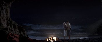 Movie still from “50 First Dates” (2004), directed by Peter Segal – A man and a woman standing next to a fire on the beach; Wide shot, High angle