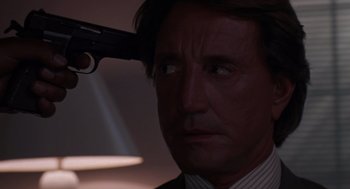Movie still from “52 Pick-Up” (1986), directed by John Frankenheimer – A person holding a gun over their head; Close Up shot, Low angle