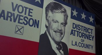 Movie still from “52 Pick-Up” (1986), directed by John Frankenheimer – A poster of a man with a mustache; Close Up shot, Low angle