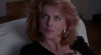 Movie still from “52 Pick-Up” (1986), directed by John Frankenheimer – A person with a wine glass; Close Up shot, Over the shoulder angle