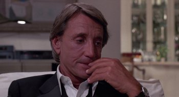 Movie still from “52 Pick-Up” (1986), directed by John Frankenheimer – A person wearing a suit and tie; Close Up shot, Over the shoulder angle