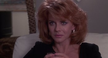 Movie still from “52 Pick-Up” (1986), directed by John Frankenheimer – A person sitting on a couch; Close Up shot, Over the shoulder angle