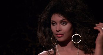 Movie still from “52 Pick-Up” (1986), directed by John Frankenheimer – A woman with big hair and big gold earrings; Close Up shot, Over the shoulder angle
