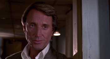 Movie still from “52 Pick-Up” (1986), directed by John Frankenheimer – A person wearing a suit and tie; Close Up shot, Over the shoulder angle