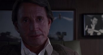 Movie still from “52 Pick-Up” (1986), directed by John Frankenheimer – A person wearing a suit and tie; Close Up shot, Over the shoulder angle