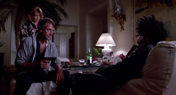 Movie still from “52 Pick-Up” (1986), directed by John Frankenheimer – Two men sitting on a couch in a living room; Medium shot, Over the shoulder angle