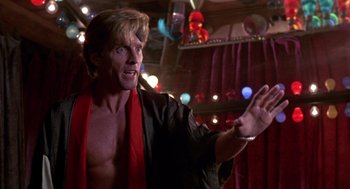 Movie still from “52 Pick-Up” (1986), directed by John Frankenheimer – A man with a red scarf on his neck and arms outstretched; Close Up shot, Low angle