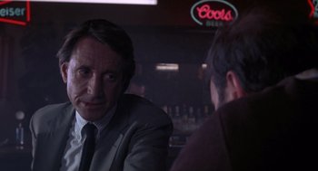 Movie still from “52 Pick-Up” (1986), directed by John Frankenheimer – A man wearing a suit and tie talking to another man; Close Up shot, Over the shoulder angle