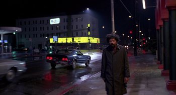 Movie still from “52 Pick-Up” (1986), directed by John Frankenheimer – A man standing on the side of the road at night; Wide shot, Low angle