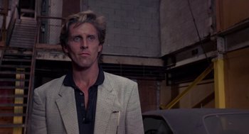 Movie still from “52 Pick-Up” (1986), directed by John Frankenheimer – A man wearing a suit and tie in a room; Close Up shot, Low angle