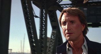 Movie still from “52 Pick-Up” (1986), directed by John Frankenheimer – A person with a bridge in the background; Close Up shot, Low angle