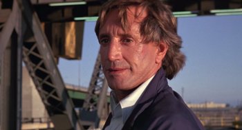 Movie still from “52 Pick-Up” (1986), directed by John Frankenheimer – A person wearing a suit and tie; Close Up shot, Low angle