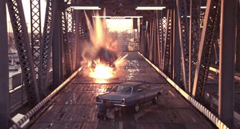 Movie still from “52 Pick-Up” (1986), directed by John Frankenheimer – A car is on fire on a bridge; Extreme Wide shot, Overhead angle