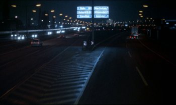 Movie still from “71 Fragments of a Chronology of Chance” (1994), directed by Michael Haneke – A street with a lot of traffic at night time; Extreme Wide shot, High angle