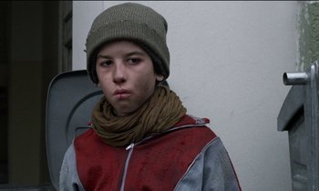 Movie still from “71 Fragments of a Chronology of Chance” (1994), directed by Michael Haneke – A young man wearing a hat and a scarf; Close Up shot, Low angle