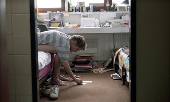 Movie still from “71 Fragments of a Chronology of Chance” (1994), directed by Michael Haneke – A man in striped shirt standing in a bedroom; Wide shot, High angle