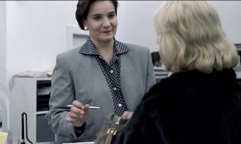 Movie still from “71 Fragments of a Chronology of Chance” (1994), directed by Michael Haneke – A woman in a gray jacket is talking to a woman in a black polka dot shirt; Close Up shot, Over the shoulder angle