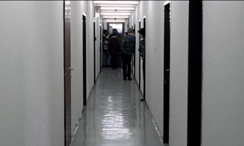 Movie still from “71 Fragments of a Chronology of Chance” (1994), directed by Michael Haneke – People are walking down a long hallway in an office building; Wide shot, High angle