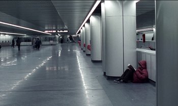 Movie still from “71 Fragments of a Chronology of Chance” (1994), directed by Michael Haneke – A person sitting on the floor of a subway station; Extreme Wide shot, High angle