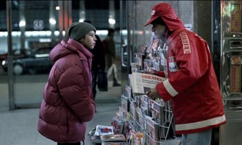 Movie still from “71 Fragments of a Chronology of Chance” (1994), directed by Michael Haneke – A woman in a red jacket talking to a man in a red jacket; Medium shot, Over the shoulder angle