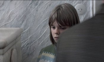 Movie still from “71 Fragments of a Chronology of Chance” (1994), directed by Michael Haneke – A young girl looking at the camera with a sad look on her face; Close Up shot, Over the shoulder angle