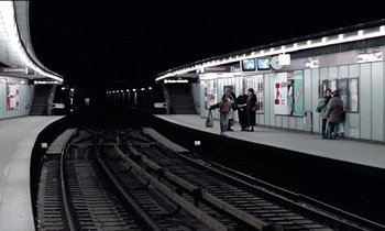 Movie still from “71 Fragments of a Chronology of Chance” (1994), directed by Michael Haneke – Two people are standing on the platform waiting for a train; Extreme Wide shot, High angle