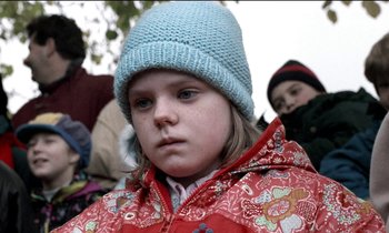 Movie still from “71 Fragments of a Chronology of Chance” (1994), directed by Michael Haneke – A little girl wearing a blue hat and a red jacket; Close Up shot, Over the shoulder angle