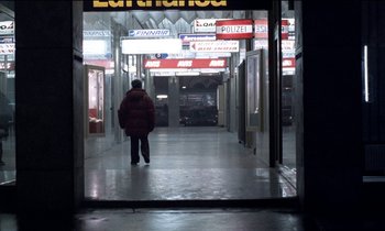 Movie still from “71 Fragments of a Chronology of Chance” (1994), directed by Michael Haneke – A man walking down a hallway in a building; Extreme Wide shot, High angle