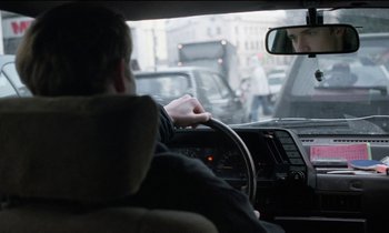 Movie still from “71 Fragments of a Chronology of Chance” (1994), directed by Michael Haneke – A man driving a car in the middle of the street; Close Up shot, Over the shoulder angle