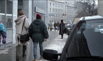 Movie still from “71 Fragments of a Chronology of Chance” (1994), directed by Michael Haneke – A couple of people walking down a street; Wide shot, Over the shoulder angle