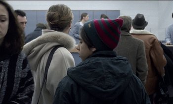 Movie still from “71 Fragments of a Chronology of Chance” (1994), directed by Michael Haneke – A group of people sitting in a room; Close Up shot, Over the shoulder angle