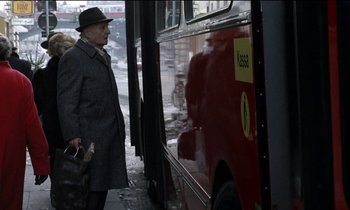 Movie still from “71 Fragments of a Chronology of Chance” (1994), directed by Michael Haneke – A man standing next to a bus on a city street; Medium shot, Over the shoulder angle