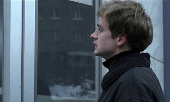 Movie still from “71 Fragments of a Chronology of Chance” (1994), directed by Michael Haneke – A man looking out of a window at a building; Close Up shot, Over the shoulder angle