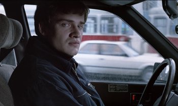Movie still from “71 Fragments of a Chronology of Chance” (1994), directed by Michael Haneke – A man sitting in the driver's seat of a car; Close Up shot, Over the shoulder angle