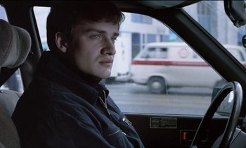 Movie still from “71 Fragments of a Chronology of Chance” (1994), directed by Michael Haneke – A man sitting in the driver's seat of a car; Close Up shot, Over the shoulder angle