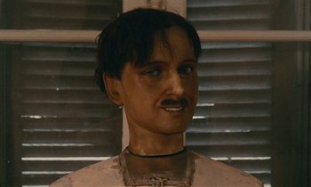 Movie still from “7 Rm., kit., ba...” (1984), directed by Agnès Varda – A wax figure of a man with a mustache; Close Up shot, Low angle