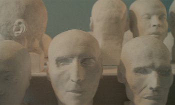 Movie still from “7 Rm., kit., ba...” (1984), directed by Agnès Varda – View of a group of heads; Extreme Close Up shot, Low angle