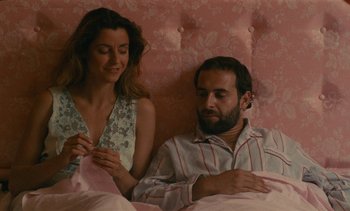 Movie still from “7 Rm., kit., ba...” (1984), directed by Agnès Varda – A man and a woman sitting in a bed; Medium shot, High angle