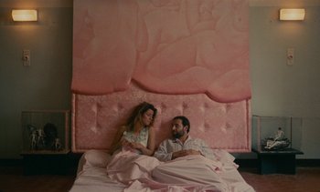 Movie still from “7 Rm., kit., ba...” (1984), directed by Agnès Varda – A man and a woman laying in a bed together; Wide shot, High angle