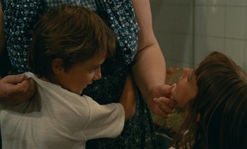 Movie still from “7 Rm., kit., ba...” (1984), directed by Agnès Varda – A woman and a boy are playing with a cat; Close Up shot, Over the shoulder angle