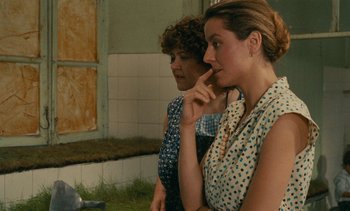 Movie still from “7 Rm., kit., ba...” (1984), directed by Agnès Varda – Two women sitting next to each other in front of a window; Medium shot, Over the shoulder angle