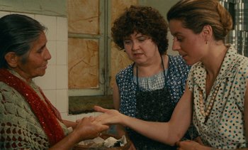 Movie still from “7 Rm., kit., ba...” (1984), directed by Agnès Varda – Two women and a man in a kitchen; Medium shot, High angle
