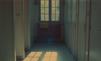Movie still from “7 Rm., kit., ba...” (1984), directed by Agnès Varda – A hallway with a radiator and a window; Extreme Wide shot, High angle