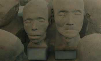 Movie still from “7 Rm., kit., ba...” (1984), directed by Agnès Varda – A couple of busts of a man and a woman; Extreme Close Up shot, Low angle