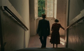 Movie still from “7 Rm., kit., ba...” (1984), directed by Agnès Varda – A man and a woman walking up a flight of stairs; Wide shot, High angle