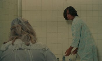 Movie still from “7 Rm., kit., ba...” (1984), directed by Agnès Varda – A woman is in a bathroom with a remote control; Medium shot, Over the shoulder angle