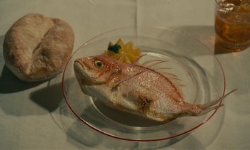 Movie still from “7 Rm., kit., ba...” (1984), directed by Agnès Varda – A plate with a fish on it on a table; Extreme Close Up shot, High angle