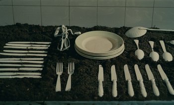 Movie still from “7 Rm., kit., ba...” (1984), directed by Agnès Varda – A bunch of silverware is laying out on the ground; Extreme Close Up shot, Overhead angle